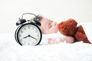 The little boy slept in bed with a teddy bear sleeping as a friend. He is sick with a cold. The morning clock at 8.20 a.m. Childcare Concept photo