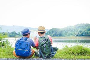 Two boys carrying backpack traveling nature Sitting and holding a paper map to study the route. Concept of child development photo
