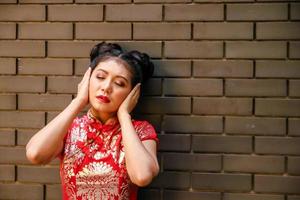 A Chinese woman wearing a red dress, covering her ears with both hands. New year festival photo