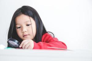 The little girl enjoys studying science. She holds a magnifying glass. Concept of child education development photo