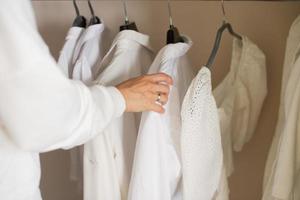 A girl in white clothes hangs light things in a closet on a hanger photo