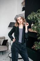 a girl in a beret holds her hair with her hands and looks into the frame photo