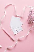 Stickers for writing with a pen on a pink background next to a white ribbon and white flowers photo