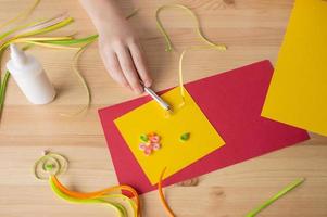 Making a postcard from long and narrow strips of paper twisted into spirals, a quilling tool photo