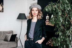 a girl in a beret holds her hair with her hands and looks into the frame photo