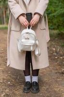 Body part of a girl with a backpack and a drink cup in her hands photo