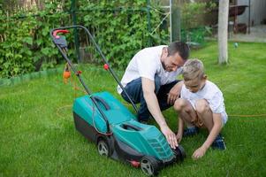 Dad and his curious son mow the lawn. Disassemble the lawn mower photo