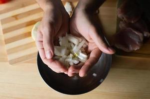 Men's hands hold pieces of onion near the bowl photo