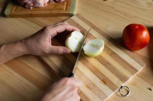 Men's hands cut onions on a wooden board photo