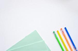 un conjunto de papelería en un blanco fondo, plumas de diferente colores foto