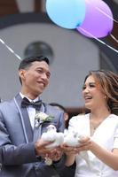 The bride and groom carry a pair of pigeons and balloons photo