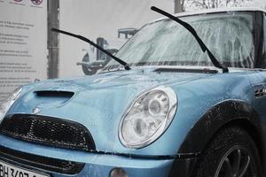 Hand wash with soap, pink foam on the body. Car washing with high pressure water. Wash Mini Cooper. photo