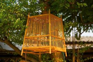 Wooden bird cage for standing or hanging with feeding compartment. The cage is entirely made of teak wood. Suitable for all types of birds. Soft and selective focus. photo
