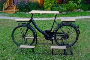 inventions to reduce global warming By bringing an old bicycle to design as a table with 2 seats in the middle as a table Placed on the lawn. Soft and selective focus. photo