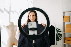 Beautiful Asian lady blogger showing clothes in front of the camera to recording vlog photo