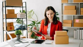 Small business entrepreneur SME freelance woman working at home office, BOX,tablet and laptop online, marketing, packaging, delivery, e commerce concept photo