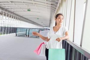 Portrait of happy smiling woman with shopping bags in corridor walk way. Beautiful woman with a paper bag. photo