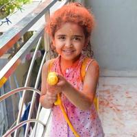 Sweet little Indian girl playing colours on Holi festival, holding pichakaree full of colours, Holi festival celebrations in Delhi, India photo