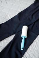 roller for cleaning clothes from dust and pellets on dark trousers, top view photo