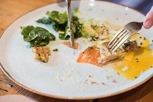 Leftovers from a hearty dinner of egg, red fish, avocado and greens in a restaurant photo