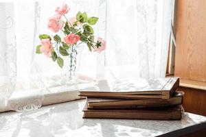 vintage brown photo albums stand on the table in a stack near the window with flowers on the windowsill