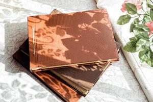 old brown photo albums are stacked on the table by the window, top view