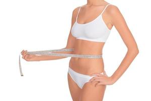 ajuste joven mujer medición su cintura foto