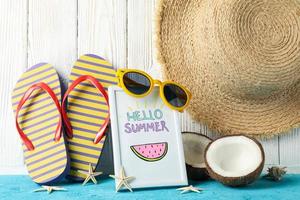 Frame with Hello summer and vacation accessories on wooden background, close up