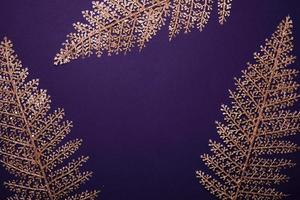 Christmas violet background. Shining golden floral frame made of leaves
