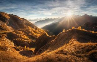 Mountains in low clouds at beautiful sunset in autumn in Italy photo