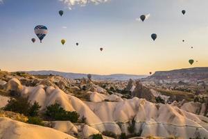 Hot air balloons flying over a volcanic landscape at Cappadocia, Turkey