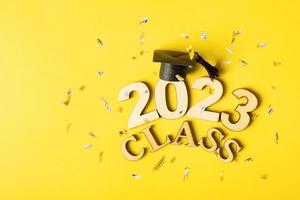 Class of 2023 concept. Wooden number 2023 with graduated cap on colored background photo