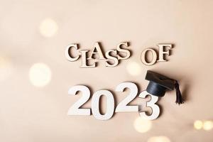 Class of 2023 concept. Wooden number 2023 with graduated cap on colored background photo