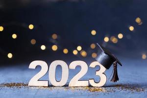 clase de 2023 concepto. de madera número 2023 con graduado sombrero en oscuro antecedentes con bokeh foto