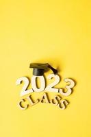 Class of 2023 concept. Wooden number 2023 with graduated cap on colored background photo