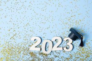 Class of 2023 concept. Wooden number 2023 with graduated cap on colored background. photo