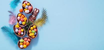 Easter banner eggs hunt concept with flat lay chocolate eggs and bunny on blue background with copy space photo