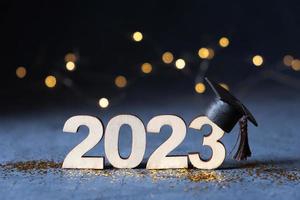 clase de 2023 concepto. de madera número 2023 con graduado sombrero en oscuro antecedentes con bokeh foto