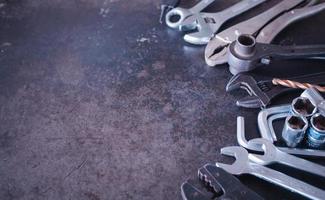 Hand tools consisting of wrenches, pliers, socket wrenches, laid out on old steel plate background. photo