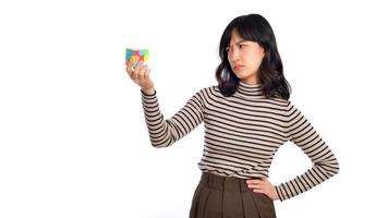 Asian woman holding a puzzle cube standing on white background. solving cubic problems, problem solution and making strategic moves concept photo