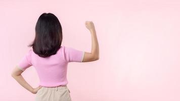 Portrait back of woman proud and confident showing strong muscle strength arms flexed posing, feels about her success achievement. Women empowerment, equality, healthy strength and courage concept photo