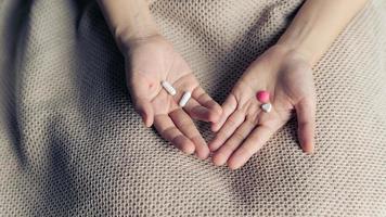 Female hands hold and offer two choice medicine pills capsule for chosen. White and pink candy or meds compare to choose from. Concept decision making or indecisiveness. photo