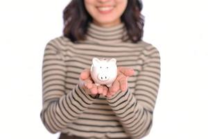 retrato de joven asiático mujer casual uniforme participación blanco cerdito banco aislado en blanco fondo, financiero y banco ahorro dinero concepto foto