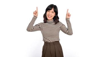 Beautiful young Asian woman on sweater cloth pointing fingers up and looking at camera with smile face and happy. click on link above gesture on white background