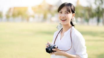 retrato de asiático mujer viajero utilizando cámara. Asia verano turismo vacaciones concepto con el grandioso palacio en un antecedentes a bangkok, Tailandia foto