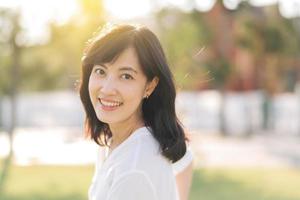 Portrait young beautiful asian woman with happy smile around outdoor park in sunny summer day photo