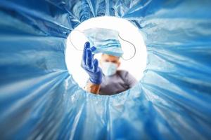 A blue-gloved man throws a used medical mask in the trash, a view from the bucket. photo