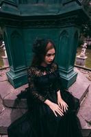 an Asian woman dressed all in black was sitting in a cemetery with a very scary expression while attending the death of her brother photo