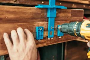 carpenter use a cabinet hardware jig adjustable punch locator drill guide sleeve for Install cabinet handles and knobs ,DIY maker and woodworking concept. selective focus photo