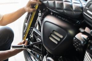 mechanic using tape measure set up suspension sag Compression and Rebound on motorcycle at garage,  repair and maintenance motorcycle concept .selective focus photo